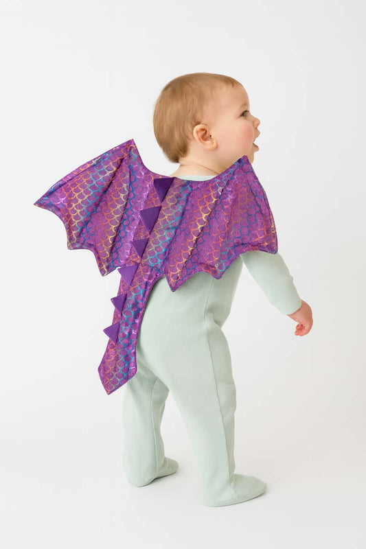 Baby wearing a purple dragon costume on a white background
