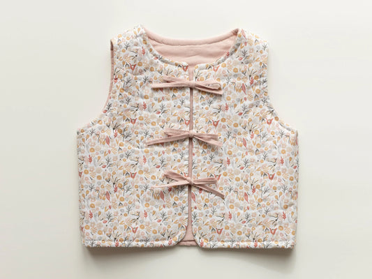 Floral-patterned children's vest with pink ribbons on a light background