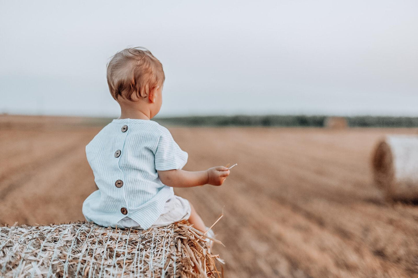 Child sitting on a hay bale in a field