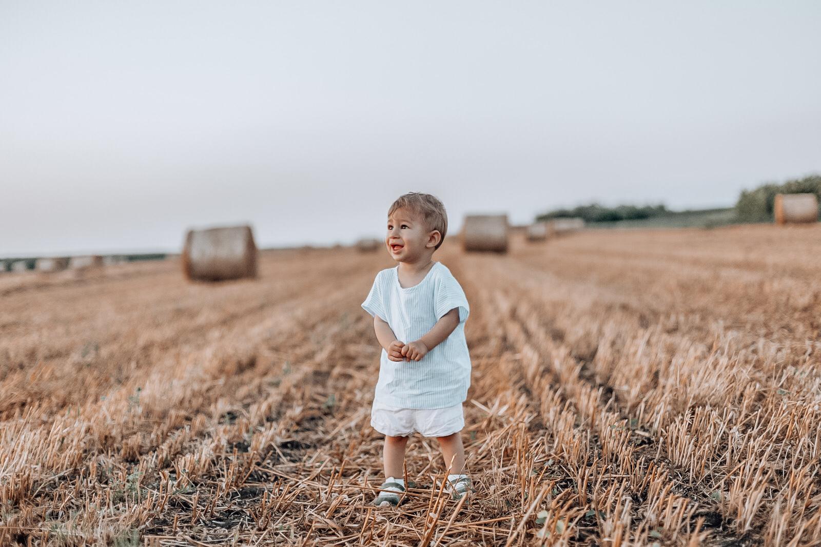 Child standing in a field with hay bales in the background