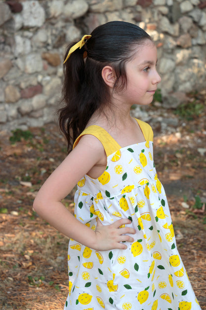 Easy beginner children’s sewing pattern for a classic dress with wide shoulder straps, empire waist, gathered skirt, and open back with bow tie detail.
