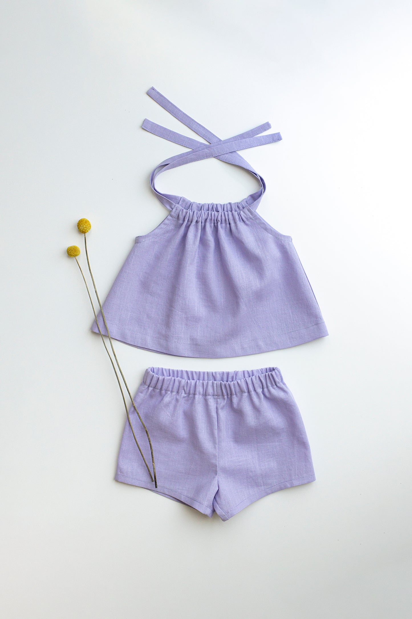 Lavender top and shorts set on a white background with small yellow flowers.