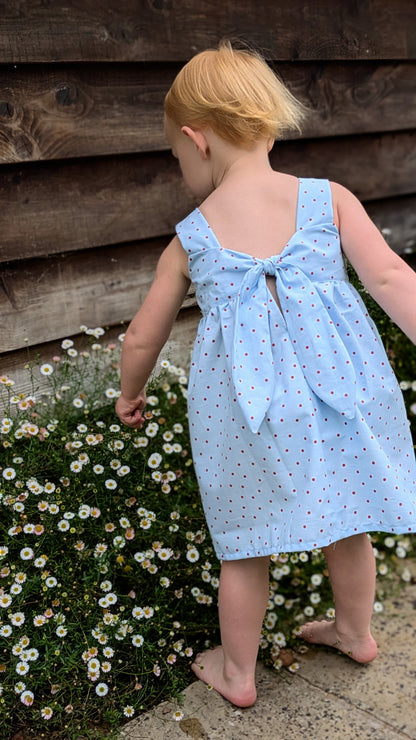 Easy beginner children’s sewing pattern for a classic dress with wide shoulder straps, empire waist, gathered skirt, and open back with bow tie detail.