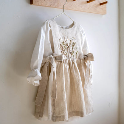 White dress with beige skirt on a hanger against a white wall
