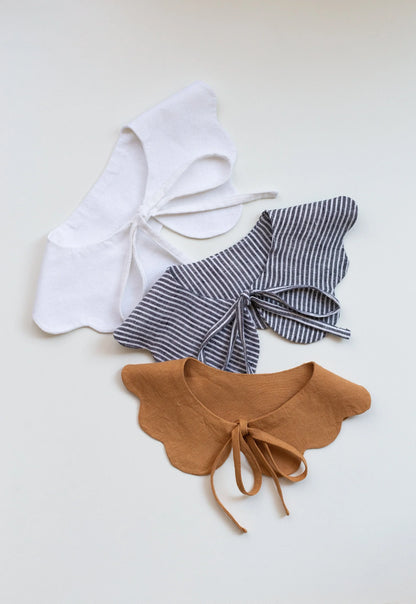 Three decorative bows in white, black and white striped, and brown on a light gray background