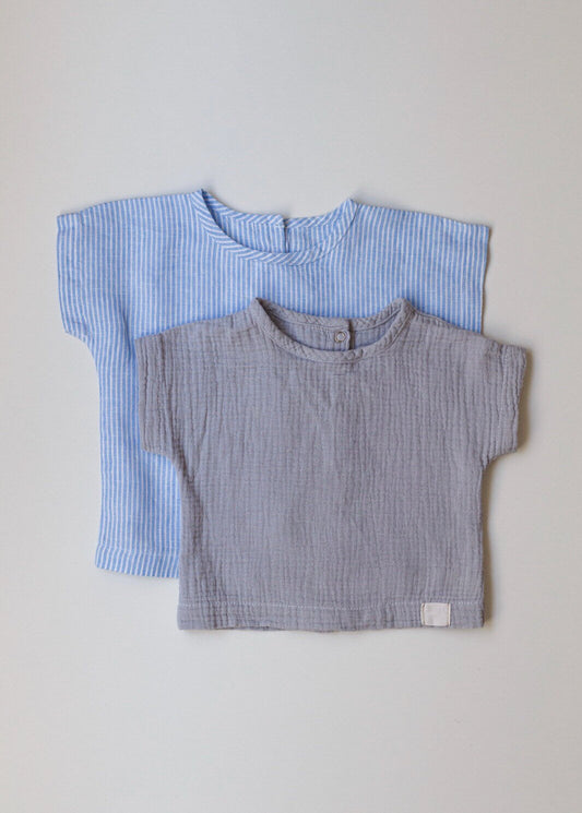 Two folded shirts, one blue and one gray, on a light gray background