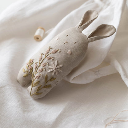 Decorative rabbit-shaped pillow with floral embroidery on a white fabric background