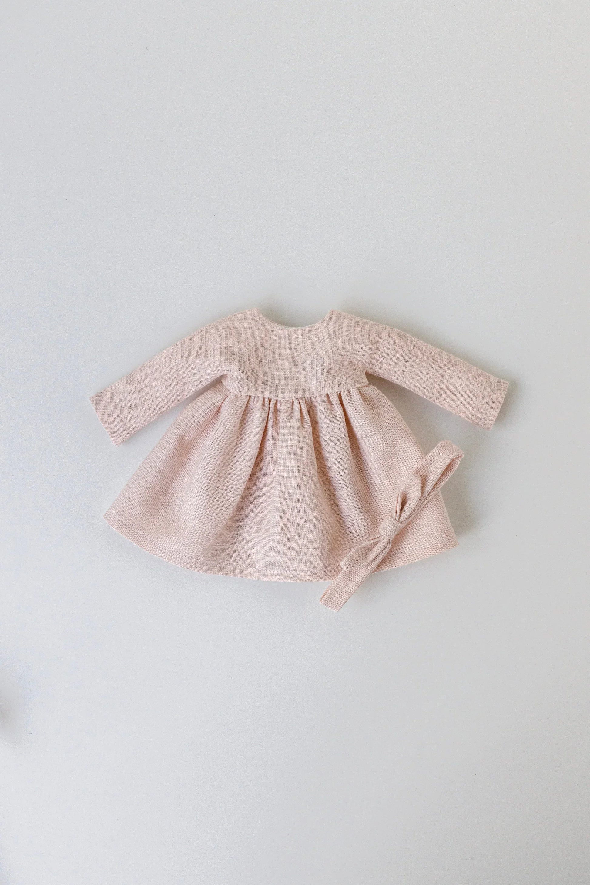 Pink baby dress with matching headband on a light gray background