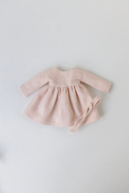 Pink baby dress with matching headband on a light gray background