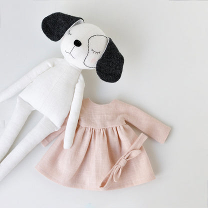 Stuffed dog toy with a pink dress on a white background