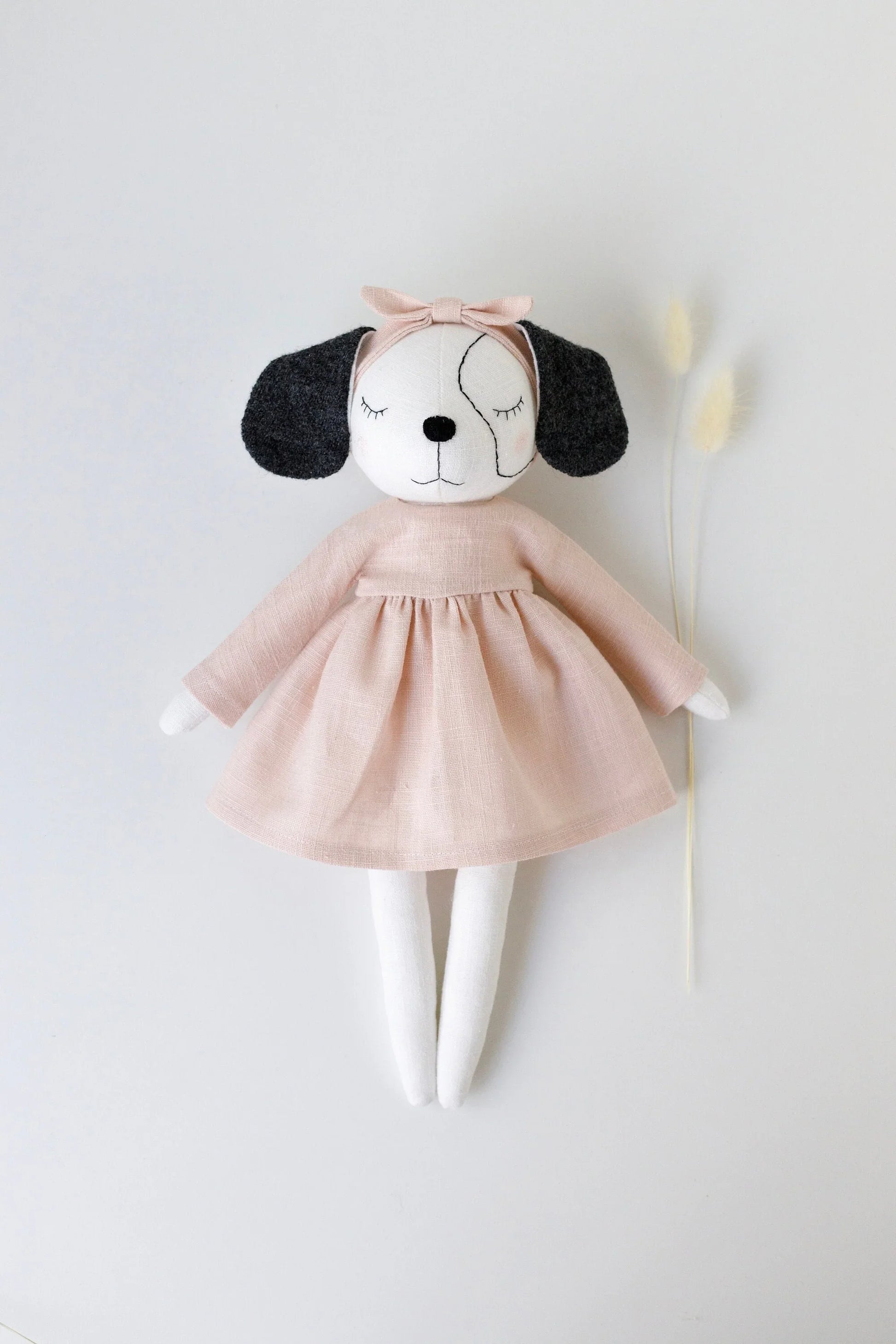 Stuffed dog toy with a pink dress on a white background