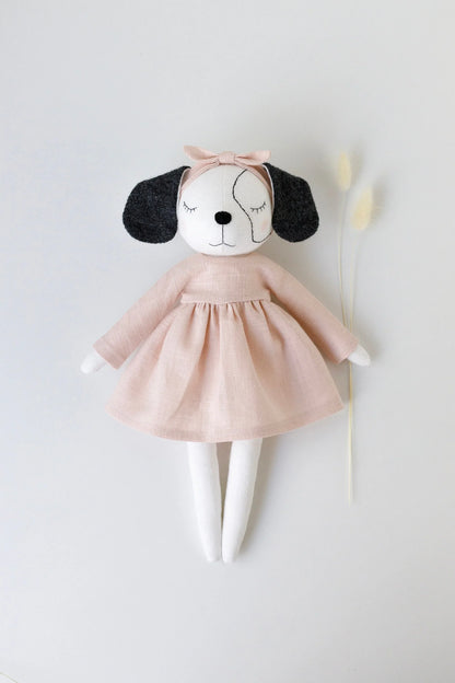 Stuffed dog toy with a pink dress on a white background