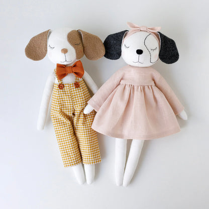 Two plush dog toys, one in a brown outfit with a bow tie and the other in a pink dress, on a white background.