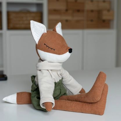 Stuffed fox toy with a white scarf sitting on a white surface