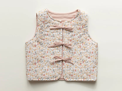 Floral-patterned children's vest with pink ribbons on a light background