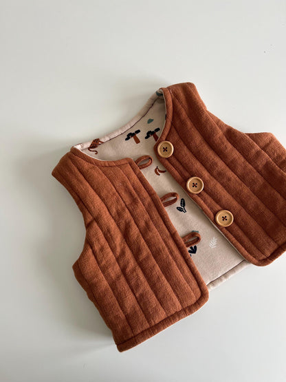Brown quilted vest with buttons on a light gray background